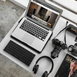 Overhead view of a modern workspace featuring a laptop, camera, and accessories.